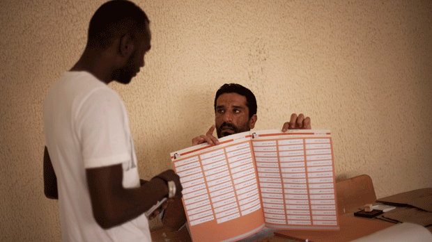 An election official shows a man how to fill out a ballot at a polling station in Tripoli, Libya, Saturday, July 7, 2012. (AP Photo/Manu Brabo)