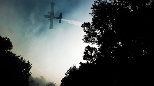 A plane works to extinguish a wildfire in La Gomera, Spain on Sunday, Aug. 12, 2012. (AP Photo/Andres Gutierrez)