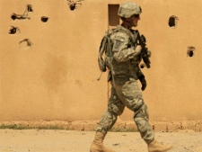 A U.S. Army soldier from A Co. 1st Battalion, 14th Infantry Regiment, 2nd Brigade, 25th Infantry Division, passes a bullet-riddled wall during a patrol in Hawija, north of Baghdad, Iraq on Tuesday, Aug. 31, 2010. (AP / Maya Alleruzzo)