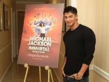 In this publicity image released by Cirque du Soleil, Jamie King, writer and director of "Michael Jackson The Immortal World Tour" by Cirque du Soleil, stands by a promotional poster, Wednesday, Nov. 3, 2010 in Los Angeles where the Estate of Michael Jackson and Cirque du Soleil announced the launch of the production combining Michael Jackson music and choreography with Cirque du Soleil performers. (AP Photo/Cirque du Soleil, Jake Novak)