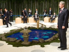 Prime Minister Stephen Harper stands next to a fake lake in the middle of the metting room at APEC meetings in Yokohama, Japan Saturday Nov.13, 2010. The fake lake was made of televisions with digital fish and lilly pads. Adrian Wyld/THE CANADIAN PRESS