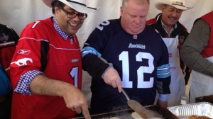 Calgary Mayor Naheed-Nenshi (left) and Toronto Mayor Rob Ford (right) flip pancakes at a Grey Cup event at Nathan Phillips Square Saturday. (Jackie Crandles/CP24.com)
