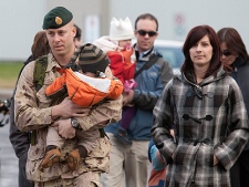 Royal 22nd Regiment Capt. Martin Rheaume carries his seven-month-old son Alexis as he and his wife Marie-Noelle Laprise, right, walk to a drill hall before leaving for Afghanistan, Monday, November 15, 2010 at CFB Valcartier Que. (THE CANADIAN PRESS/Jacques Boissinot)