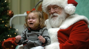 Child cries on lap of mall Santa Claus