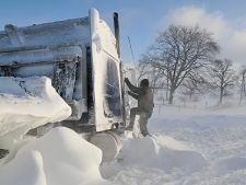 A police officer climbs on the cab of a semi to check on its driver on Tuesday Dec. 14, 2010 on London Line, East of Sarnia, Ont. A state of emergency has been declared for Lambton County as snow stranded hundreds of motorists. (THE CANADIAN PRESS/Glenn Ogilvie)