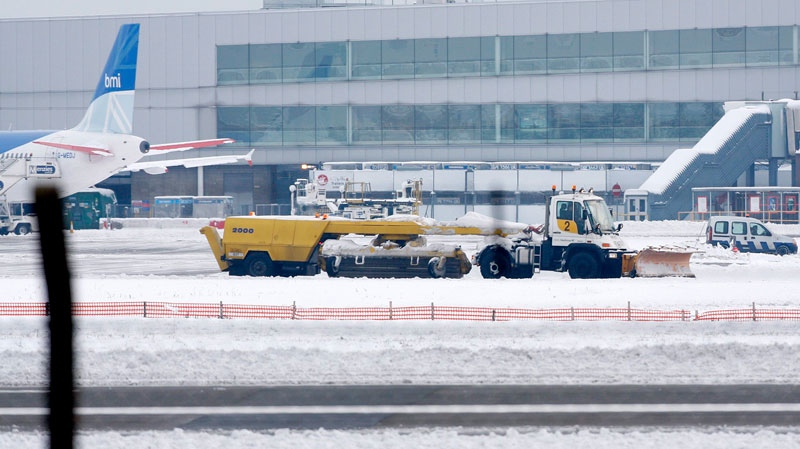 A snow plough drives past an airplane parked at Heathrow Airport in west London, Sunday, Dec. 19, 2010. (AP / Akira Suemori)