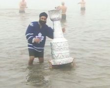 A man carrying a Stanley Cup replica submerges himself in Lake Ontario on Saturday, Jan. 1, 2011, while another Polar Bear Dip participant looks on.
