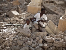 A man with two children sits in the rubble of the earthquake damaged Cathedral during a mass in Port-au-Prince, Haiti, Wednesday Jan. 12, 2011. 