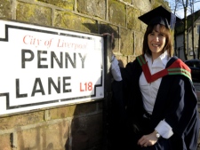 In this image made available by Liverpool Hope University on Wednesday, Jan. 26, 2011, Canadian Mary-Lu Zahalan-Kennedy poses next to the Penny Lane street sign in Liverpool, England, after becoming the first person to graduate with a master's degree in The Beatles. (AP Photo/Alan Edwards, Liverpool Hope University)