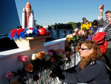 Christine Rooth, lower right, places a flower in front of the Space Mirror Memorial at a remembrance ceremony to mark the 25th Anniversary of space shuttle Challenger at the Kennedy Space Center visitor complex in Cape Canaveral, Fla., on Friday, Jan. 28, 2011. (AP Photo/John Raoux)