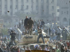 Stones fly through the air as supporters of President Hosni Mubarak, foreground, fight with anti-Mubarak protesters standing on army tanks in Cairo, Egypt on Wednesday, Feb. 2, 2011. (AP/Ahmed Ali)