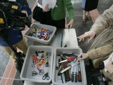 Members of the media look over scissors, knives, cigarette lighters and other items confiscated from passengers at Reagan National Airport in Washington. (AP/Pablo Martinez Monsivais)