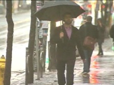 A man uses an umbrella to avoid the rain as he walks along a Toronto street Monday, Feb. 28, 2011.
