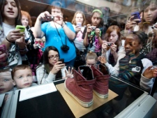 A pair of sneakers worn by Justin Bieber is encased in glass as fans crowd around to take pictures at the Bata Shoe Museum in Toronto on Monday, March 14, 2011. (THE CANADIAN PRESS/Darren Calabrese)