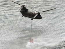 A Self-Defense Forces helicopter scoops water off Japan's northeast coast on its way to the Fukushima Dai-Ichi nuclear power plant in Okumamachi on Thursday, March 17, 2011. Helicopters are dumping water on a stricken reactor in northeastern Japan to cool overheated fuel rods inside the core. (AP Photo/Yomiuri Shimbun, Kenji Shimizu)