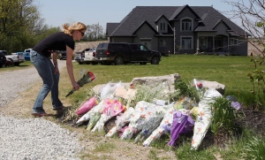 Woman lays flowers Bosma family home