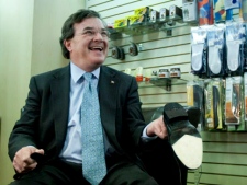 Finance Minister Jim Flaherty holds up his newly re-soled shoes during a pre-budget photo opportunity at Healthy Feet Shoe Repair in Ottawa on Monday, March 21, 2011. (THE CANADIAN PRESS/Sean Kilpatrick)