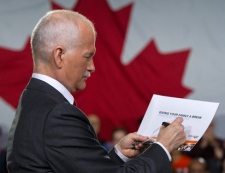 NDP Leader Jack Layton signs a copy of his election platform Sunday, April 10, 2011 in Toronto. THE CANADIAN PRESS/Paul Chiasson