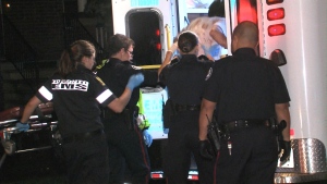 Paramedics and police assist a person who was stabbed near Queen Street West and Dowling Avenue early Thursday, July 4, 2013.