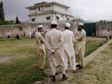 Pakistani men stand looking at the house where al-Qaida leader Osama bin Laden was caught and killed in Abbottabad, Pakistan, Thursday, May 5, 2011. The residents of Abbottabad were still confused and suspicious about the killing of bin Laden, which took place in their midst before dawn on Monday. (AP Photo/Muhammed Muheisen)
