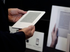 An attendee at Amazon.com Inc.'s annual shareholders meeting holds a Kindle book-reading device at a display outside the meeting hall, Tuesday, May 25, 2010, in Seattle. (AP Photo/Ted S. Warren)