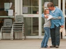 Eleven-year-old Carlee Derkoch hugs her father in Athabasca, Alta., Monday, May 23, 2011, prior to him boarding a bus to tour their burnt-out neighbourhood in Slave Lake. The trip marked the first time, since evacuating over a week ago, that Slave Lake residents have had an opportunity to see, firsthand, their devastated community. (THE CANADIAN PRESS/John Ulan)