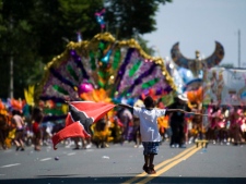 A boy carries a Trinidad and Tobago flag in front of revelers at the 2010 Caribana Parade in Toronto on Saturday, July 31, 2010. THE CANADIAN PRESS/Adrien Veczan
