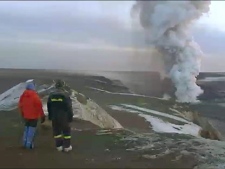 In this image from television, people watch a plume rising from the Grimsvotn volcano in Iceland Wednesday May 25 2011. Volcano experts in Iceland said that the eruption which began Saturday appeared to be tapering off. Ash from the volcano forced the cancellation of hundreds of flights over Britain on Tuesday as winds blew the ash over Scotland, but British airspace was clear on Wednesday. German air traffic control banned all takeoffs and landings at airports in Berlin, Bremen, Hamburg and Luebeck for several hours early Wednesday. (AP Photo/ RUV Iceland via APTN)