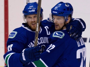 Vancouver Canucks' Daniel Sedin, right, celebrates his goal against the Calgary Flames with his teammate and twin brother, Henrik Sedin, both of Sweden, during the second period of an NHL hockey game in Vancouver, B.C., on Wednesday January 5, 2011. (THE CANADIAN PRESS/Jonathan Hayward)