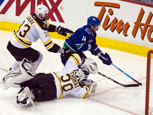 Vancouver Canucks left wing Alex Burrows skates around Boston Bruins defenseman Zdeno Chara and Bruins goalie Tim Thomas on his way to scoring the winning goal during the first overtime period in game two Stanley Cup final playoff hockey action in Vancouver, B.C., Saturday, June 4, 2011. (THE CANADIAN PRESS/Jonathan Hayward)