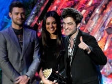Robert Pattinson accepts the award for best male performance at the MTV Movie Awards on Sunday, June 5, 2011, in Los Angeles. In background looking on are presenters Justin Timberlake and Mila Kunis. (AP Photo/Matt Sayles)