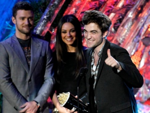 Robert Pattinson accepts the award for best male performance at the MTV Movie Awards on Sunday, June 5, 2011, in Los Angeles. In background looking on are presenters Justin Timberlake and Mila Kunis. (AP Photo/Matt Sayles)