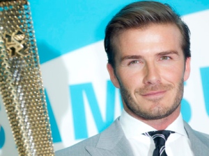 British soccer player David Beckham holds the Olympic torch at a Torchbearer nomination event in Canary Wharf, London, Monday, June 13, 2011. (AP Photo/Joel Ryan)