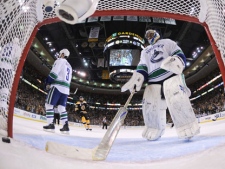 Vancouver Canucks goalie Roberto Luongo (1) reaches in with his stick to retrieve the puck as Vancouver Canucks defenseman Kevin Bieksa (3) skates off after the Bruins scored in the first period during Game 6 of the NHL hockey Stanley Cup Finals, Monday, June 13, 2011, in Boston. (AP Photo/Elsa, Pool)