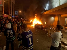 People look on during a riot in downtown Vancouver, Wednesday, June 15, 2011 following the Vancouver Canucks 4-0 loss to the Boston Bruins in game 7 of the Stanley Cup hockey final. THE CANADIAN PRESS/Ryan Remiorz