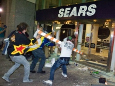 Rioters break the front doors of a Sears department store on Granville Street during the riot following Game 7 of the NHL Stanley Cup final in downtown Vancouver, B.C., on Wednesday, June 15, 2011. (THE CANADIAN PRESS/Geoff Howe)
