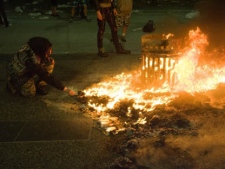 A woman lights her cigerette from a fire during a riot following Game 7 of the NHL Stanley Cup final in downtown Vancouver, B.C., on Wednesday, June 15, 2011. (THE CANADIAN PRESS/Geoff Howe)
