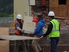 In a June 16, 2011 photo construction workers, watched by Bill Henderson, right, Quillayute Valley School District maintenance supervisor, remove the cornerstone from the 1925 portion of the Forks High School in Forks, Wash. The condition of the 86-year-old brick-and-morter facade was too poor to save without expensive renovations. The high school became famous after it was used as a setting in the Twilight series of teen romance novels. (AP Photo/Lonnie Archibald/Peninsula Daily News)