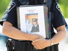 A York Regional police officer holds a program for the Remembrance Service for York Regional Police Officer Constable Garrett Styles outside the Ray Twinney Complex in Newmarket, Ontario Tuesday July 5, 2011. THE CANADIAN PRESS/Darren Calabrese