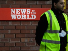 A security officer stands at the gates outside the publisher of News of the World, News International's headquarters in London, Thursday, July 7, 2011. (AP Photo/Sang Tan)