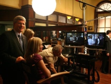 Canadian Prime Minister Stephen Harper (left) watches the taping of the Murdoch Mysteries as he watches the show's filming with his daughter Rachel (seated foreground) at the television production's studios in Toronto on Friday October 15, 2010. (THE CANADIAN PRESS/Chris Young)