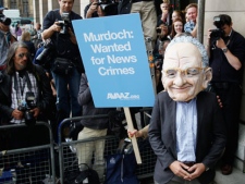 A protestor wearing a Rupert Murdoch mask is photographed by media outside parliament in London, Tuesday, July 19, 2011. Britain's Conservative Party says a former News of the World executive may have given the prime minister's former communications chief advice before the 2010 national election. The Conservative Party said Neil Wallis, who was arrested last week in Britain's phone hacking scandal, "may have provided Andy Coulson with some informal advice on a voluntary basis before the election." (AP Photo/Kirsty Wigglesworth)
