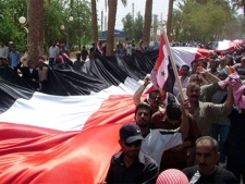 Syrian pro-government supporters carry a giant national flag during a rally in the eastern province of Deir el-Zour, Syria, Thursday, July 28, 2011. (AP / SANA)