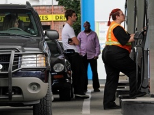Customers stand in line as Jaqueline Henderson, right, prepares to pump gas at a station in Portland, Ore., Friday, July 29, 2011. President Barack Obama and top auto executives are set to unveil details of a compromise to slash the amount of gasoline cars and trucks will need down the road. The deal will double fuel economy standards to 54.5 miles per gallon by 2025 and further restrict the tailpipe emissions blamed for global warming.(AP Photo/Don Ryan)