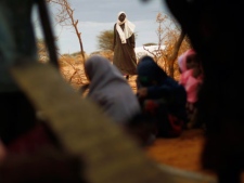 A Somali refugee looks at pupils studying the Koran at an outdoor madrasa at the Ifo camp outside Dadaab, Eastern Kenya, 100 kms (60 miles) from the Somali border, Tuesday Aug. 9, 2011. U.S. President Barack Obama has approved $105 million for humanitarian efforts in the Horn of Africa to combat worsening drought and famine. The drought and famine in the horn of Africa has killed more than 29,000 children under the age of 5 in the last 90 days in southern Somalia alone, according to U.S. estimates. The U.N. says 640,000 Somali children are acutely malnourished, suggesting the death toll of small children will rise. (AP Photo/Jerome Delay)