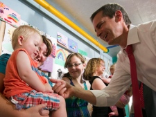 Ontario Premier Dalton McGuinty greets Grayson Gillespie, 2, as he is held by Michelle Stimson while visiting Ronald McDonald House in Toronto on Tuesday, Aug. 16, 2011. (THE CANADIAN PRESS/Frank Gunn)
