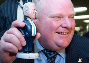 Toronto Mayor Rob Ford while Ford holds up a bobblehead doll in his likeness while signing hundreds of them for charity at City Hall in Toronto on Tuesday, November 12, 2013. (Frank Gunn/The Canadian Press)