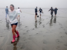 Resident Katie Austin walks in the mud after Hurricane Irene pulled all the water away and into the Albemarle Sound on the Outer Banks in Kill Devil Hills, N.C., Saturday, Aug. 27, 2011, as Hurricane Irene reaches the North Carolina coast. (AP Photo/Charles Dharapak)