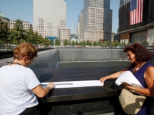 Visitors make an etching of victim's name inscribed on the wall surrounding one of the pools at the 9/11 memorial plaza in the World Trade Center site in New York on Monday, Sept. 12, 2011, on the first day that the memorial was opened to the public. (AP Photo/Mike Segar, Pool)