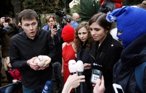 A protestor at left of the Pussy Riot punk group, who have feuded with President Vladmir Putin's government for years, disrupts their press conference while holding a chicken as Pussy Riot members Nadezhda Tolokonnikova, second from right, and Maria Alekhina, third from right, look on Thursday, Feb. 20, 2014, in Sochi, Russia. (AP Photo/David Goldman)